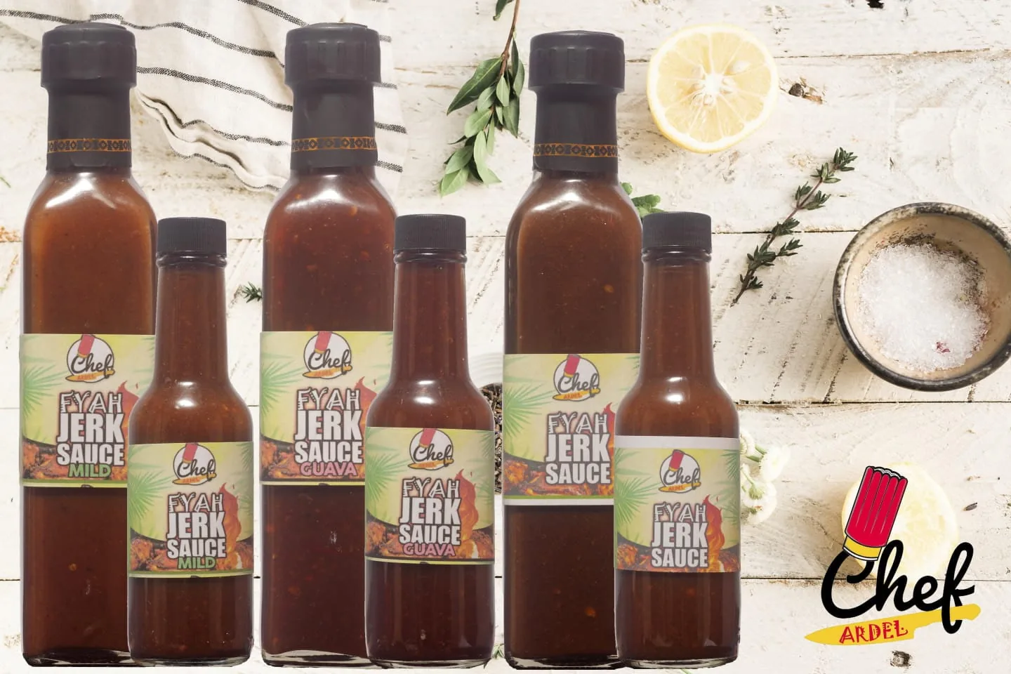 Six bottles of Fyah Jerk Sauce on a white wooden table with lemon, thyme and salt